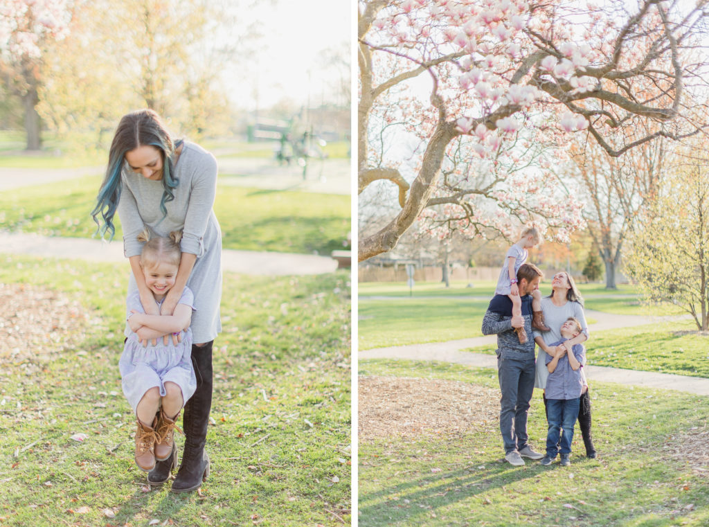 Spring Family Session, Wheaton Illinois, Northside Park. Mom is standing behind daughter, lifting her, laughing at her. Family is standing next to each other, looking and smiling at each other.