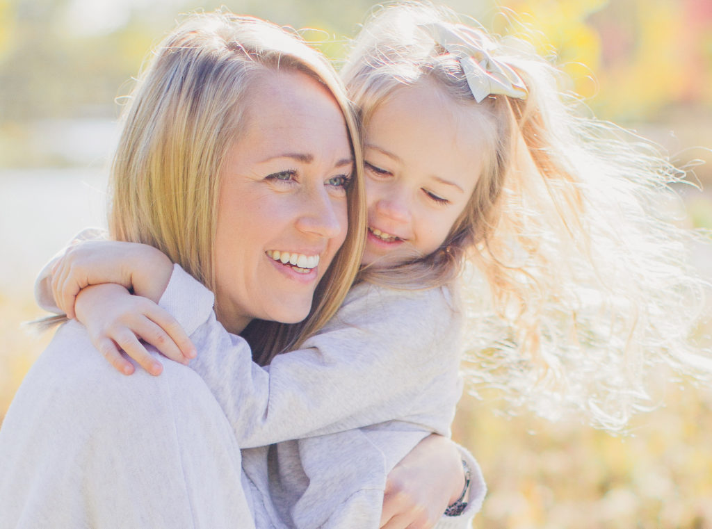 Family Photo Session. Mother is holding daughter, spinning around, laughing