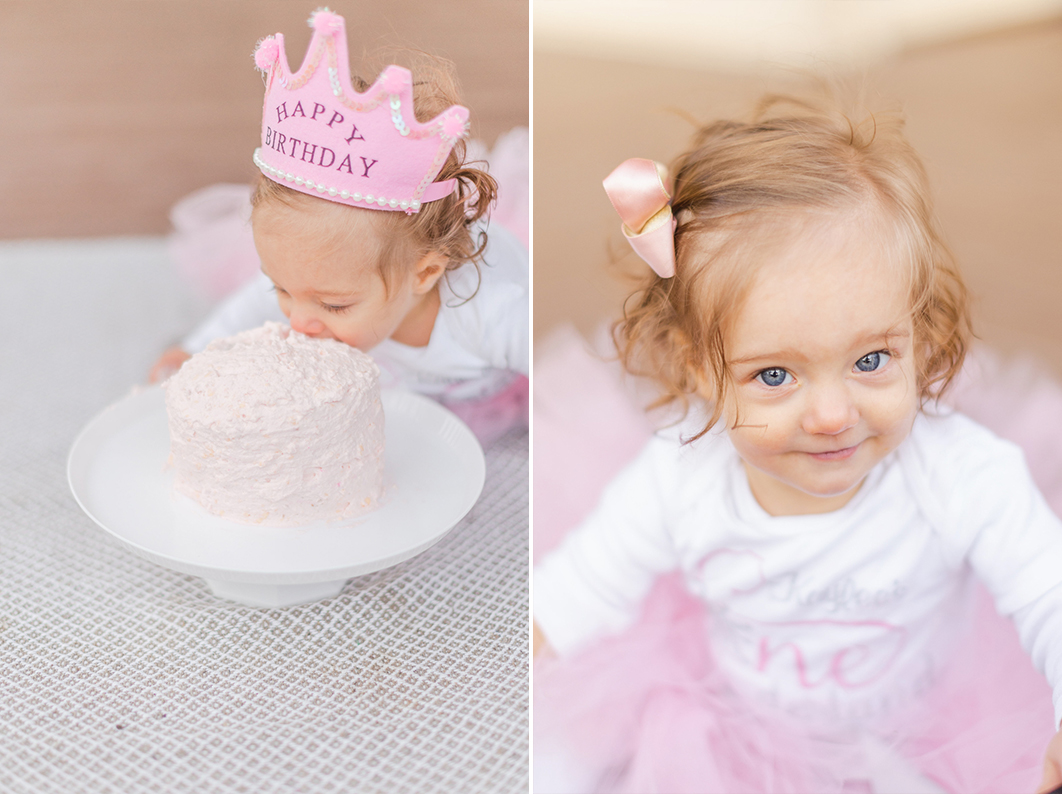 First birthday cake smash session. One year old girl is about to take her first bite of her white frosting cake, wearing a pink birthday crown.