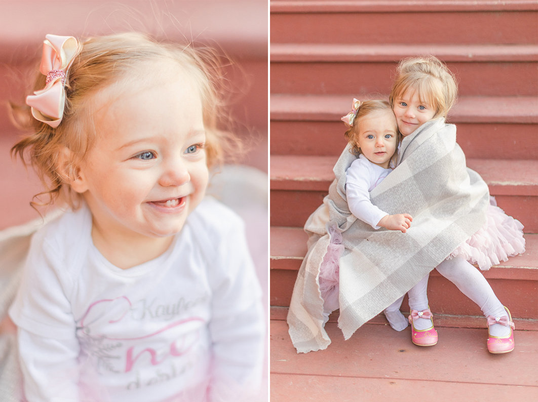 Sisters sitting on red stairs, cuddled up in a blanket and hugging each other