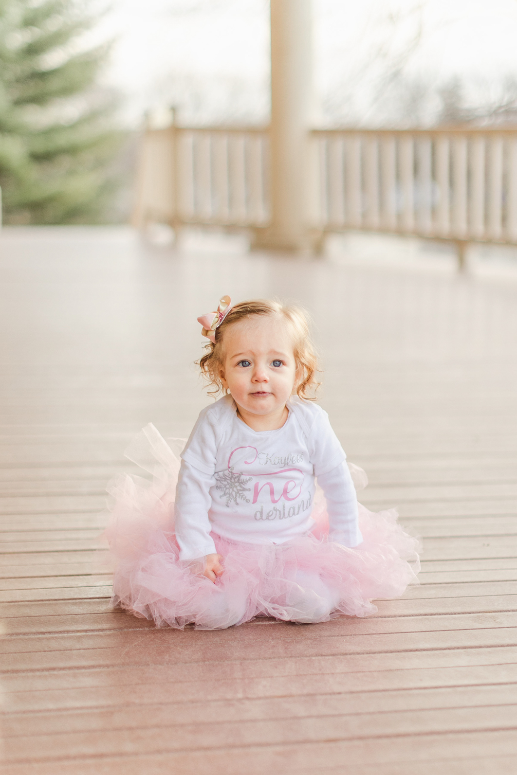 First birthday Session. One year old girl is sitting with her pink tutu starring into the camera