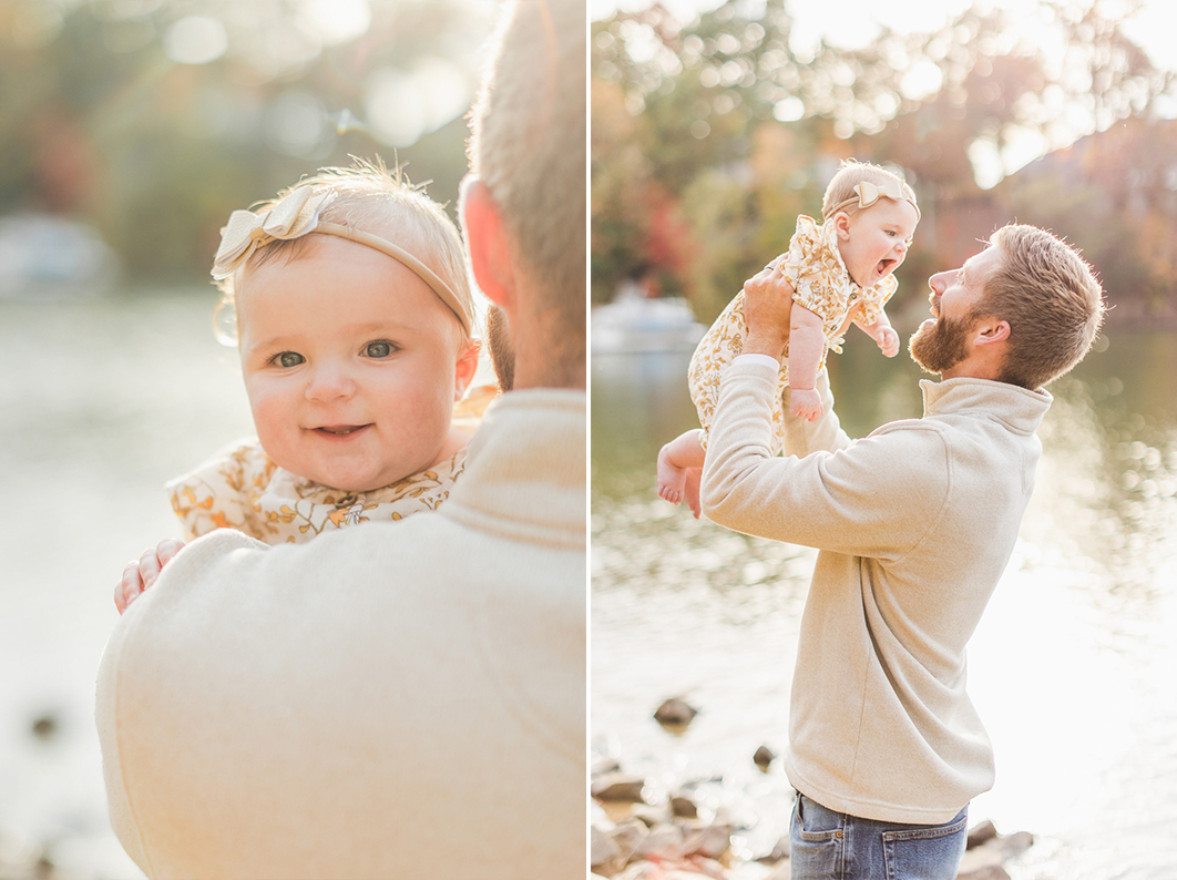 Dad is holding his six month old daughter. She is smiling over his shoulder into the camera. Dad throws his daughter up in the air, who is laughing back at him