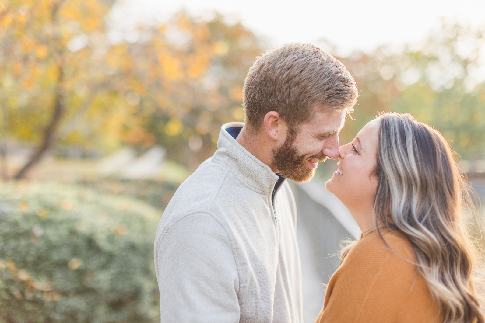 Mom and dad are standing Infront of each other, gently touching noses and smiling at each other