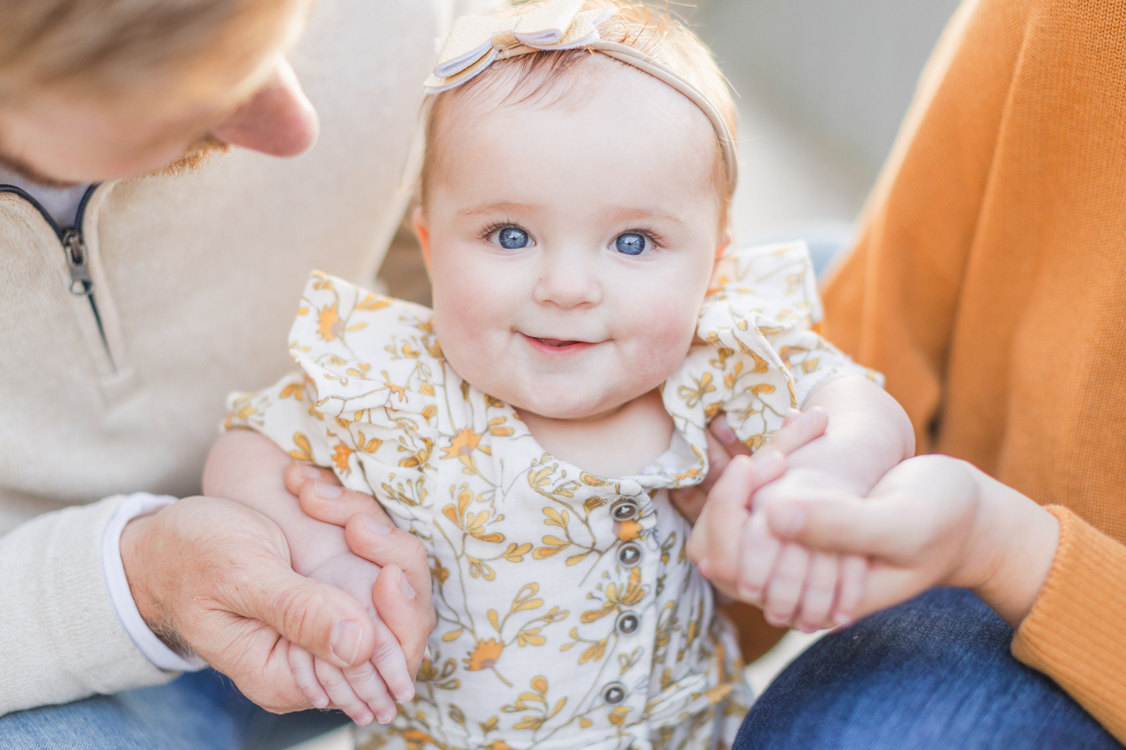 Daughter is smiling into the camera standing in between her parents