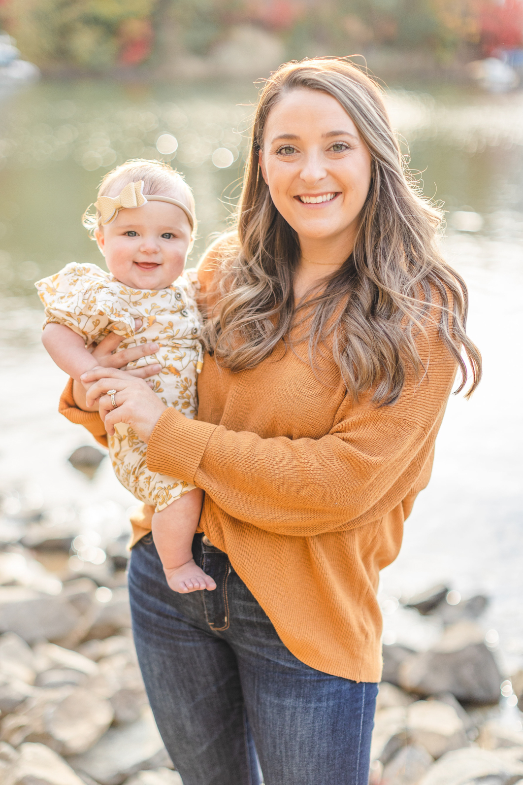 Mother and daughter. Mom is holding six month old, smiling into the camera