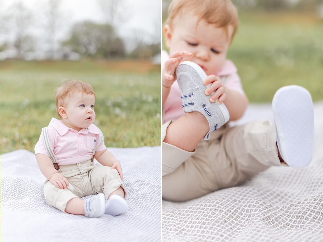 One year old is sitting on a grey blanket playing with his shoes during his mommy + me cake smash session