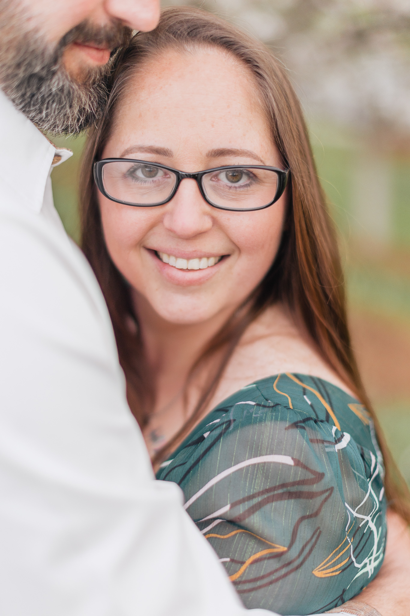 Charlotte Spring Minis - Close up of mom, while she looks into the camera, leaning on her husbands chest