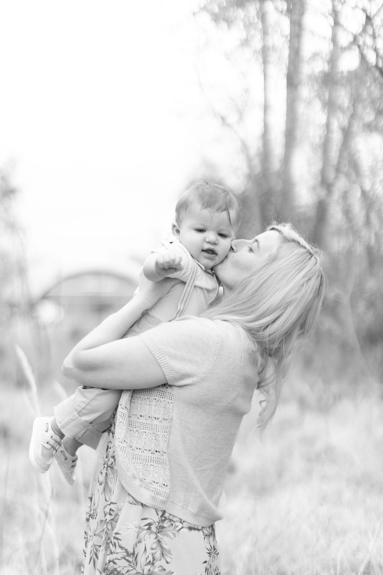 Mom is holding her one year old kissing him on the cheek during their mommy and me session