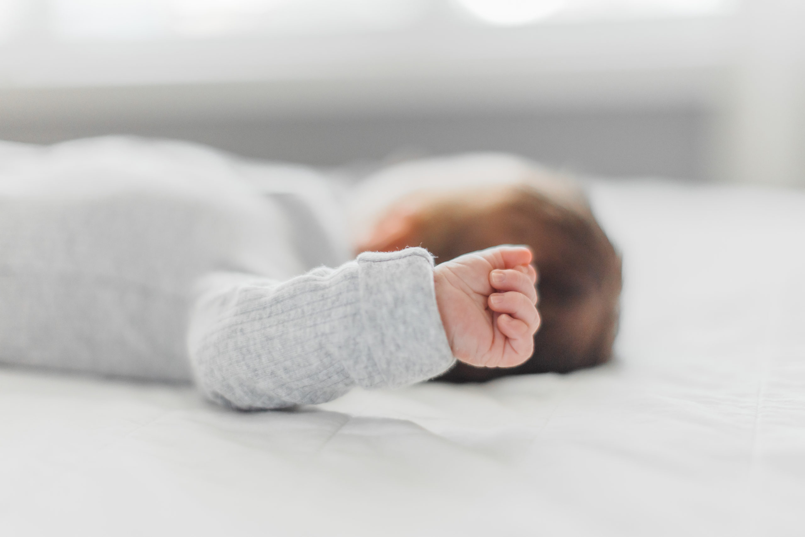 In-home newborn lifestyle session detail photo of newborns hand while laying on bed