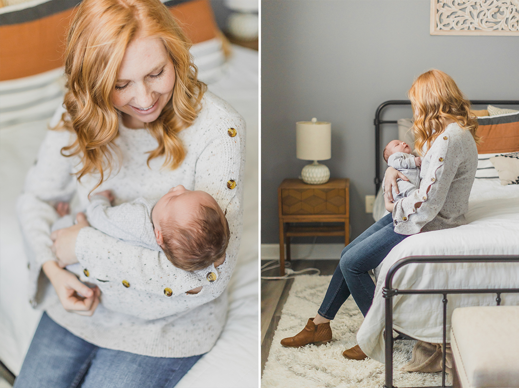 Mom is holding newborn in her arms, while sitting on the corner of her bed, smiling at the baby during the In-home newborn lifestyle session in Charlotte NC